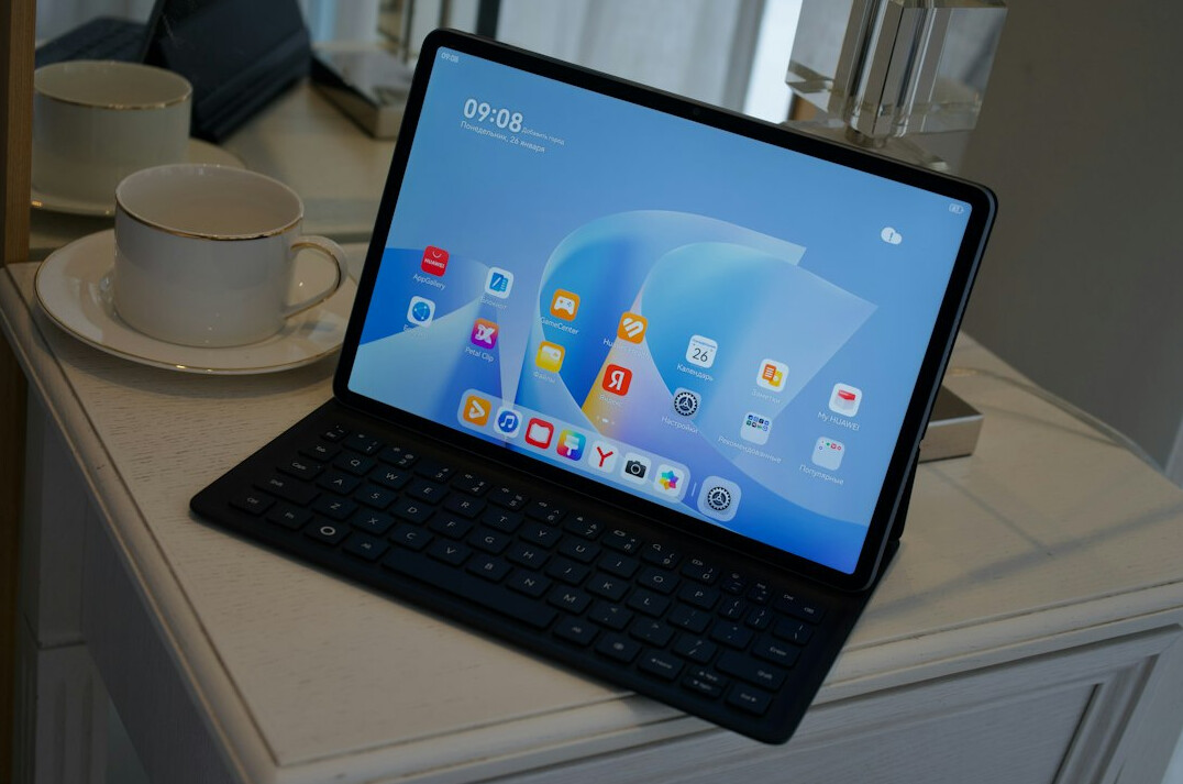 Tablet showing a video call grid on a wooden table with a cup of tea